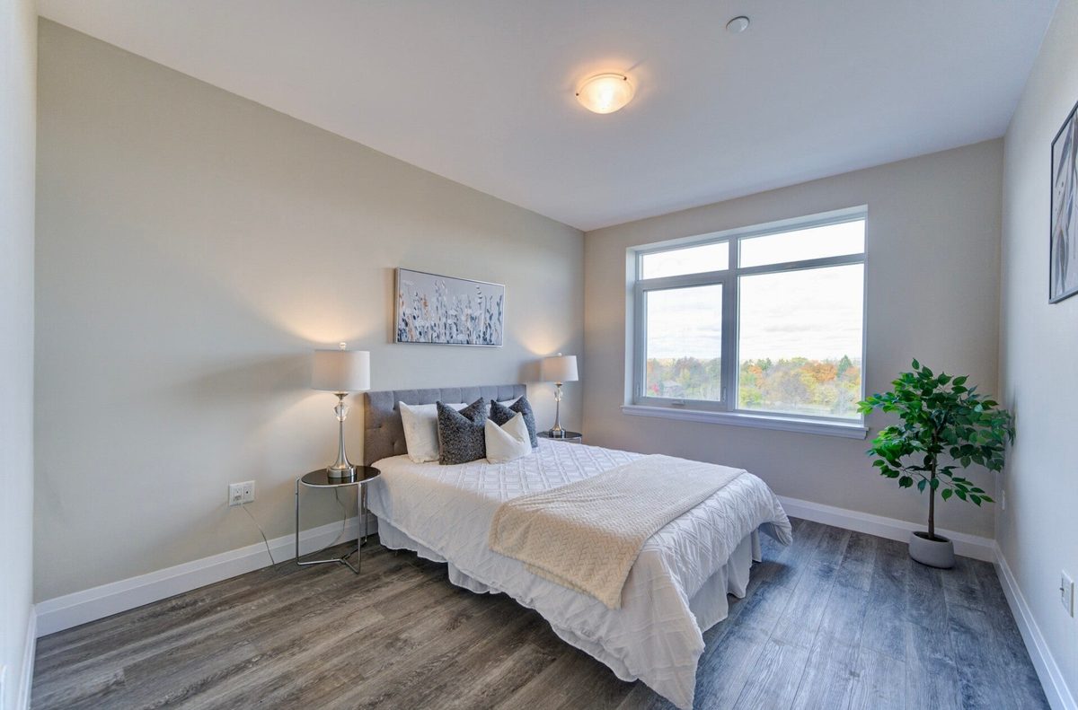 A bright cleaned bedroom with a large window looking out over autumn trees