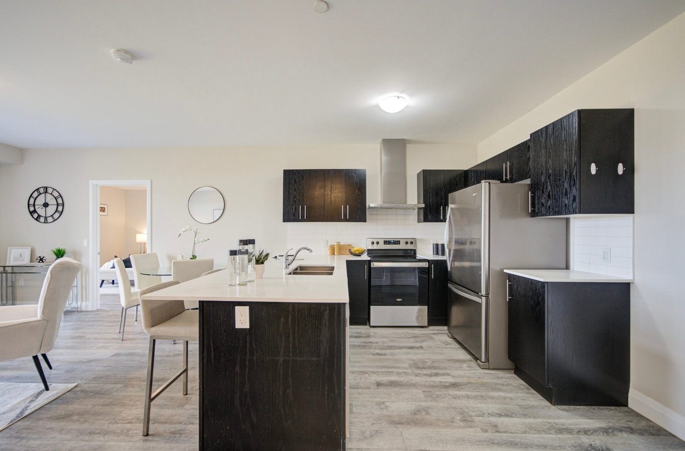 A cleaned condo kitchen with dark cabinets, a stainless fridge and range, and a clear white island counter